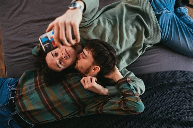 Couple gay sur lit avec iphone
