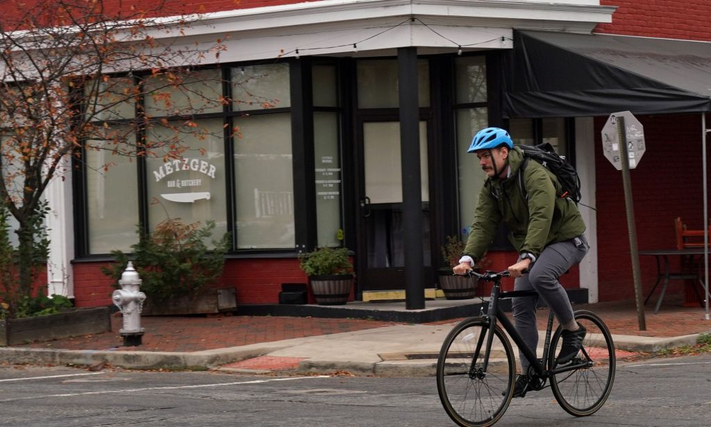 Un cycliste portant un casque bleu passe devant le bar et la boucherie Metzger, qui présentaient une impression de leur logo sur la vitre.