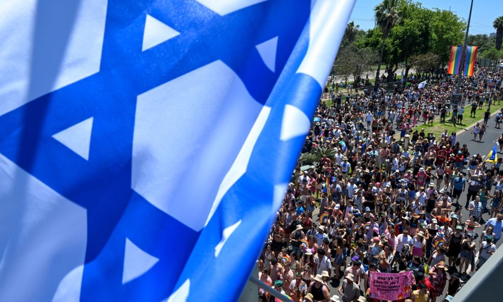 Un drapeau israélien encadre des milliers de personnes marchant dans le défilé de la fierté de Tel Aviv à Jérusalem, Israël