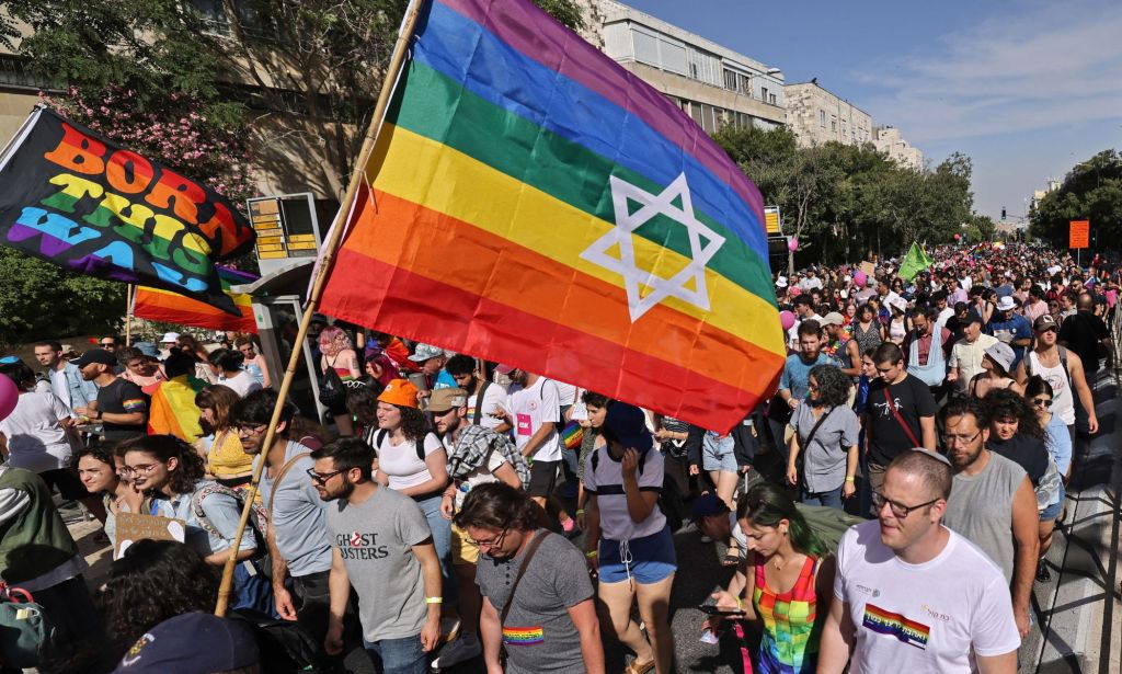 Un drapeau israélien, aux couleurs du drapeau de la fierté LGBTQ+, flotte au-dessus d'une foule de personnes défilant dans un défilé de la fierté
