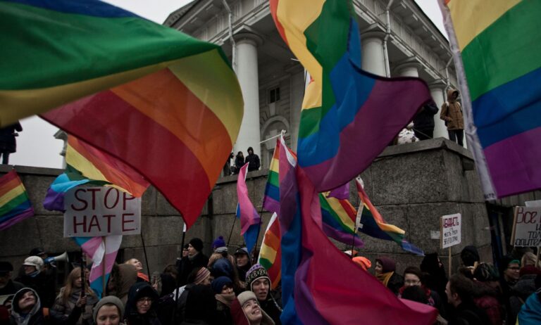 People hold up rainbow LGBTQ+ Pride flags and a sign reading 'stop hate' during a protest in Russia