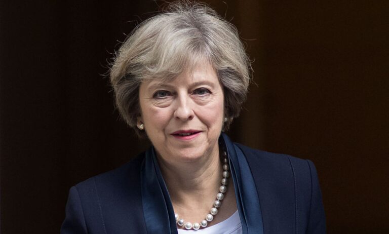A photo shows former prime minister Theresa May wearing a navy suit leaving Westminster.