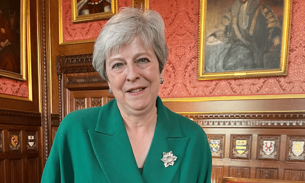 Theresa May dans une salle de la Chambre des communes bordée de portraits