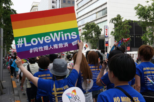 Personne tenant une affiche arc-en-ciel Love Wins pour les droits au mariage homosexuel parmi les personnes marchant dans le Tokyo Rainbow Pride (TRP) Parade 2016 à Shibuya, Tokyo, Japon.