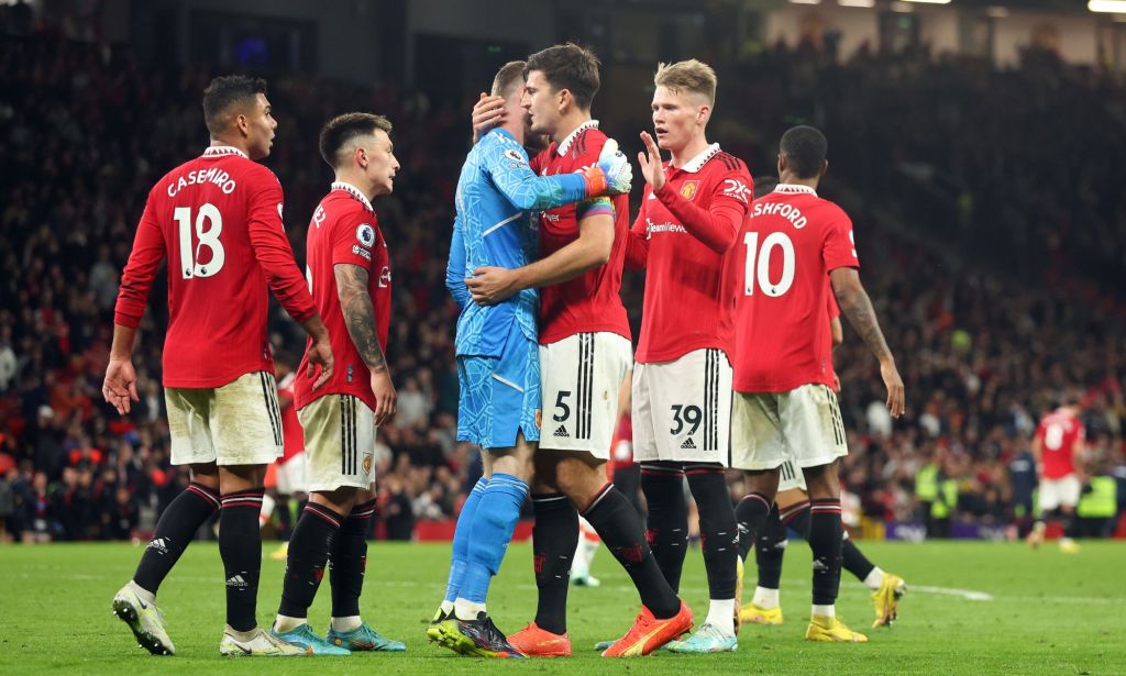 Les joueurs de Manchester United, portant des uniformes de football rouges, se rassemblent les uns autour des autres