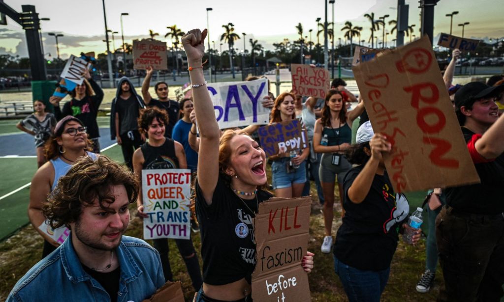 Les gens brandissent des pancartes en faveur de la communauté LGBTQ + alors qu'ils protestent contre le gouverneur de Floride Ron DeSantis, qui a défendu le projet de loi 