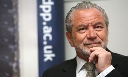 Alan Sugar in a promotional image. He is seen wearing a dark suit and tie.