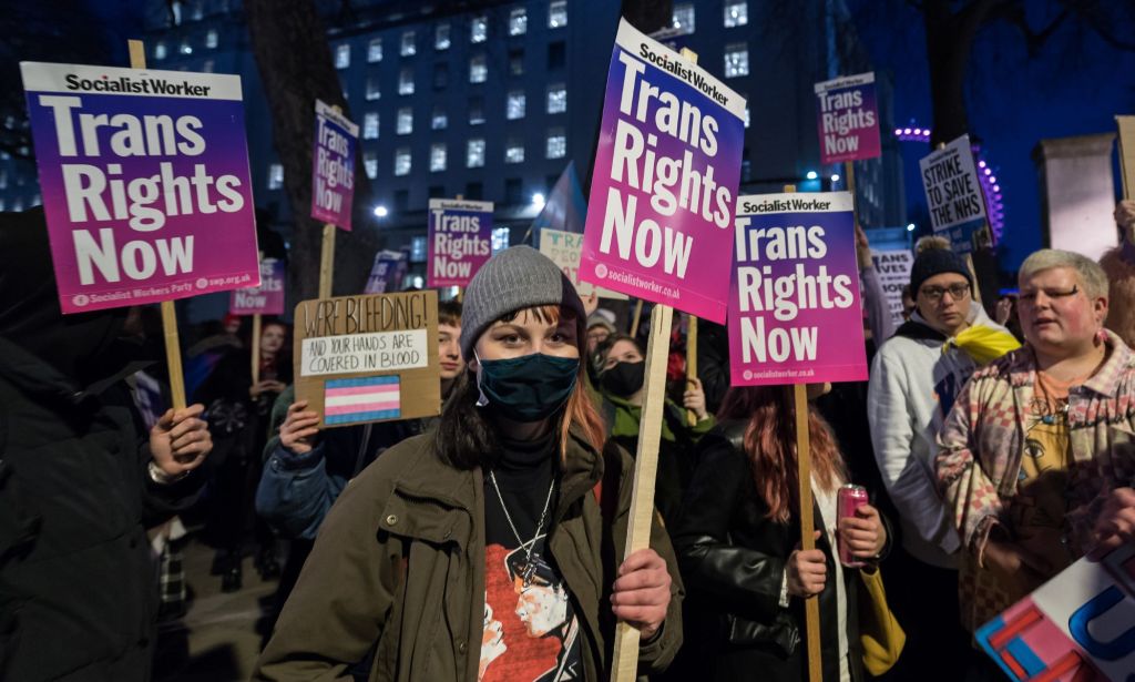 Les militants trans brandissent des pancartes indiquant "les droits des trans maintenant".