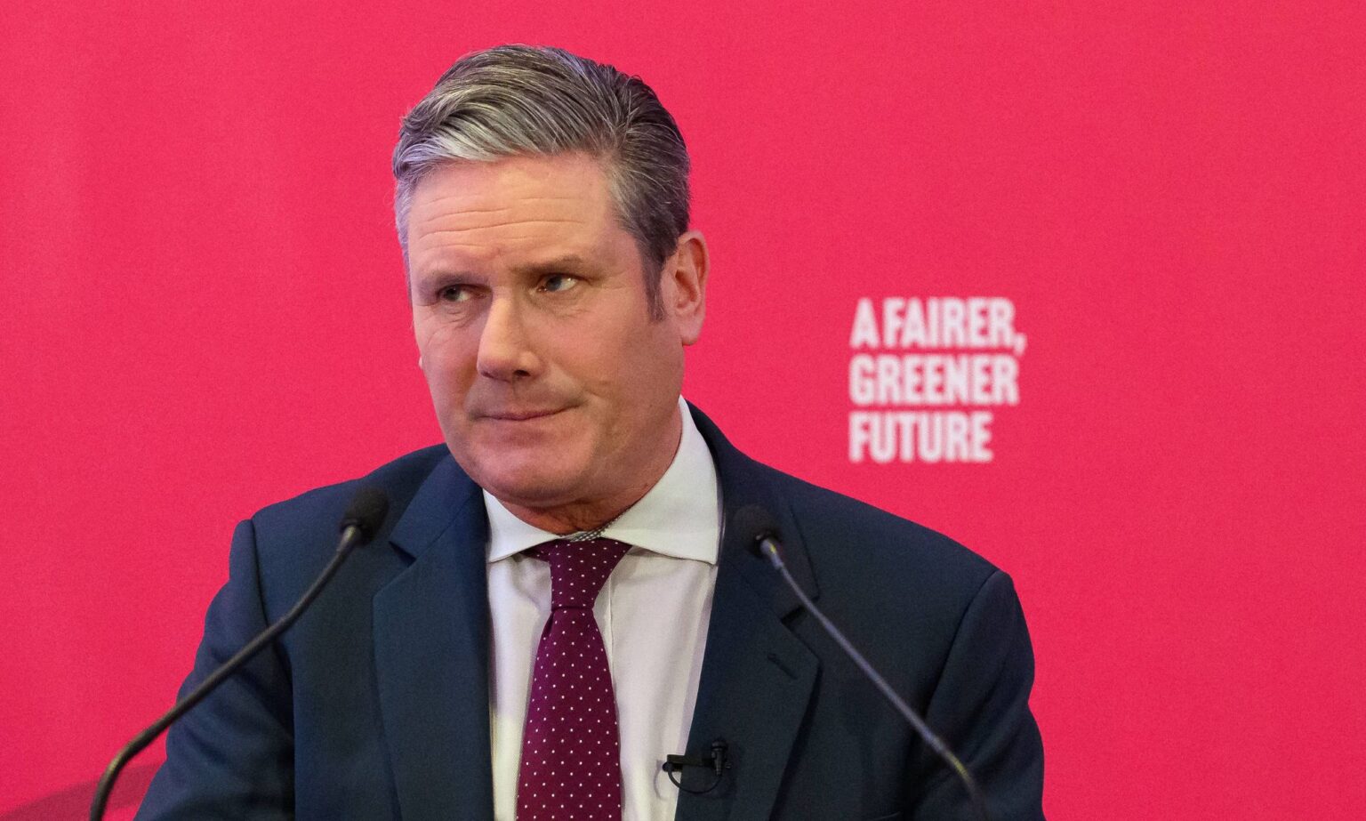 Keir Starmer signale qu’il annulera la décision du parti travailliste écossais sur les droits des trans UK Labour Party leader Keir Starmer wears a white button-up shirt, red tie and blue jacket as he speaks at an event. He is standing at a podium in front of a red background