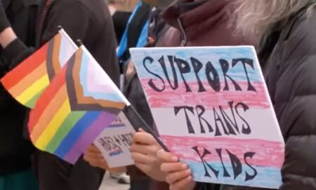 A person holds up a sign reading 'support trans kids' during a protest in Utah