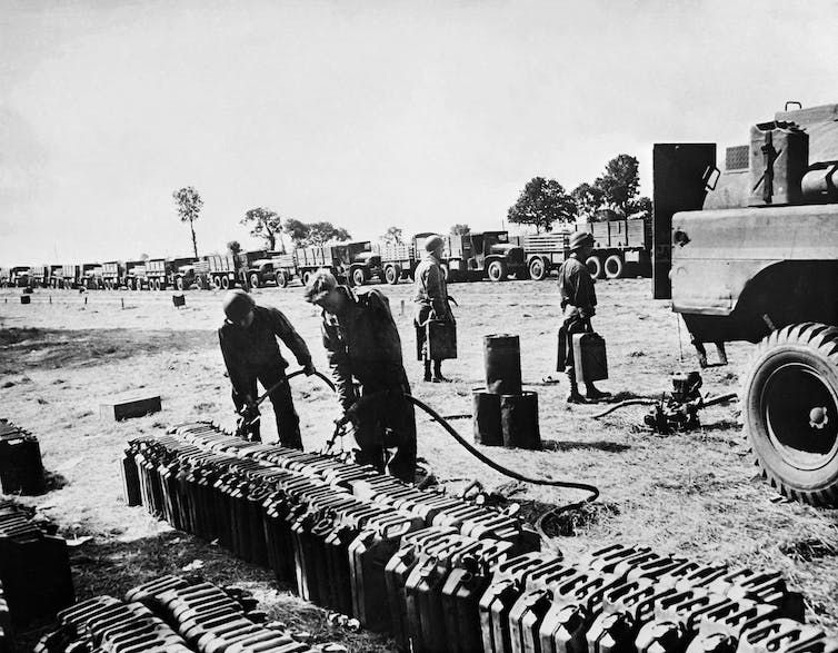On voit des soldats noirs remplir des réservoirs d'essence pour des dizaines de camions utilisés pour transporter des fournitures militaires.