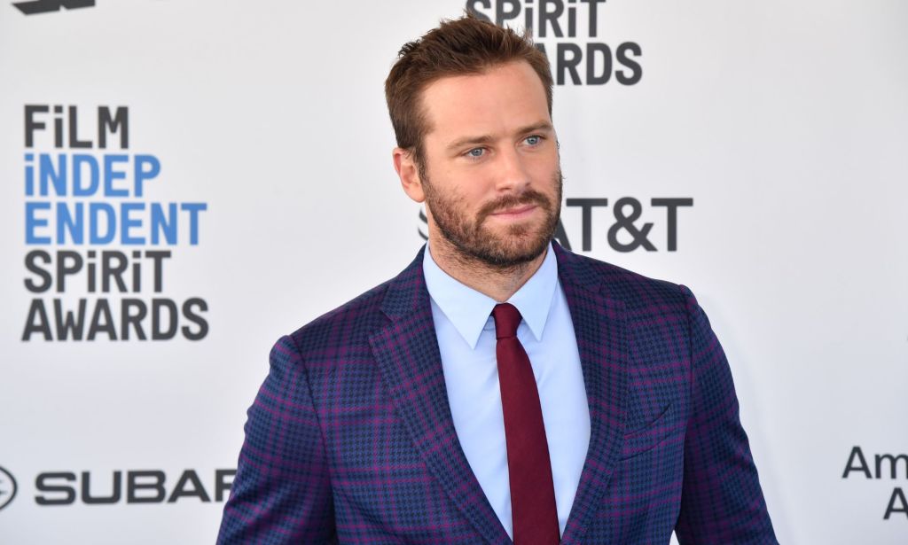 Armie Hammer se tient devant un écran de tapis rouge lors d'une séance photo.