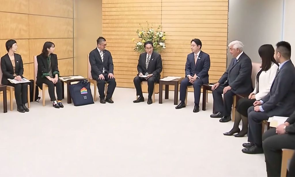 Le Premier ministre japonais Fumio Kishida est assis au centre d'un groupe de personnes alors qu'il rencontre des militants LGBTQ+