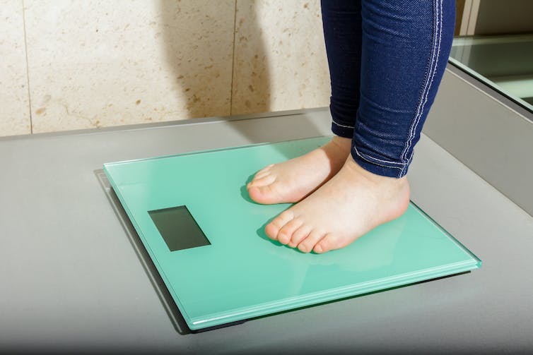Les pieds d'un enfant debout sur une balance numérique.