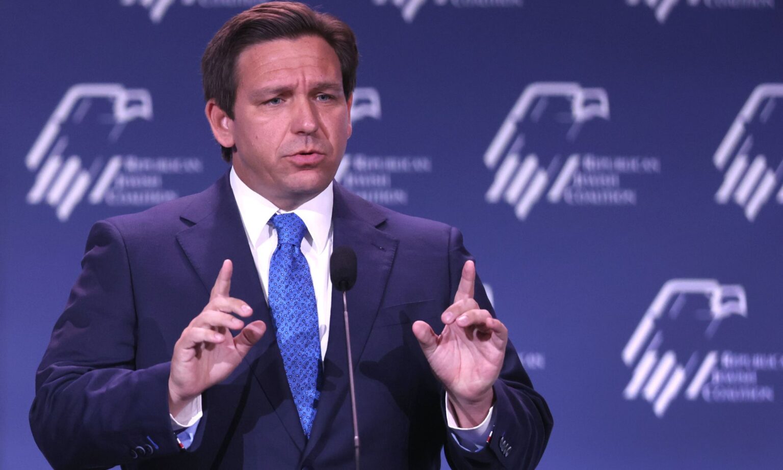 Ron DeSantis, nommé par Disney, suggère que l’eau du robinet pourrait rendre les gens homosexuels. Oui vraiment. Florida governor Ron DeSantis wears a suit and tie as he gestures with one finger raised upwards on both hands during a speech