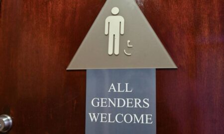 A bathroom sign with a smaller sign that reads "All genders welcome"