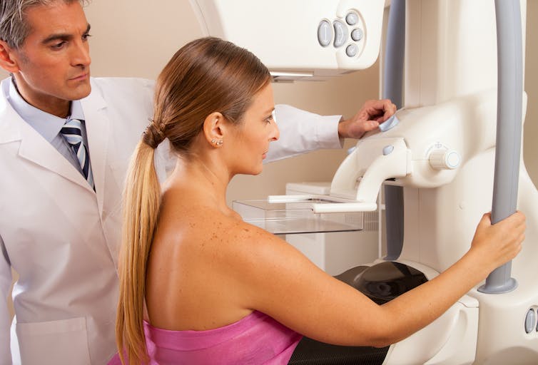 Une femme subit un examen des seins à l'aide d'une machine opérée par un médecin de sexe masculin.