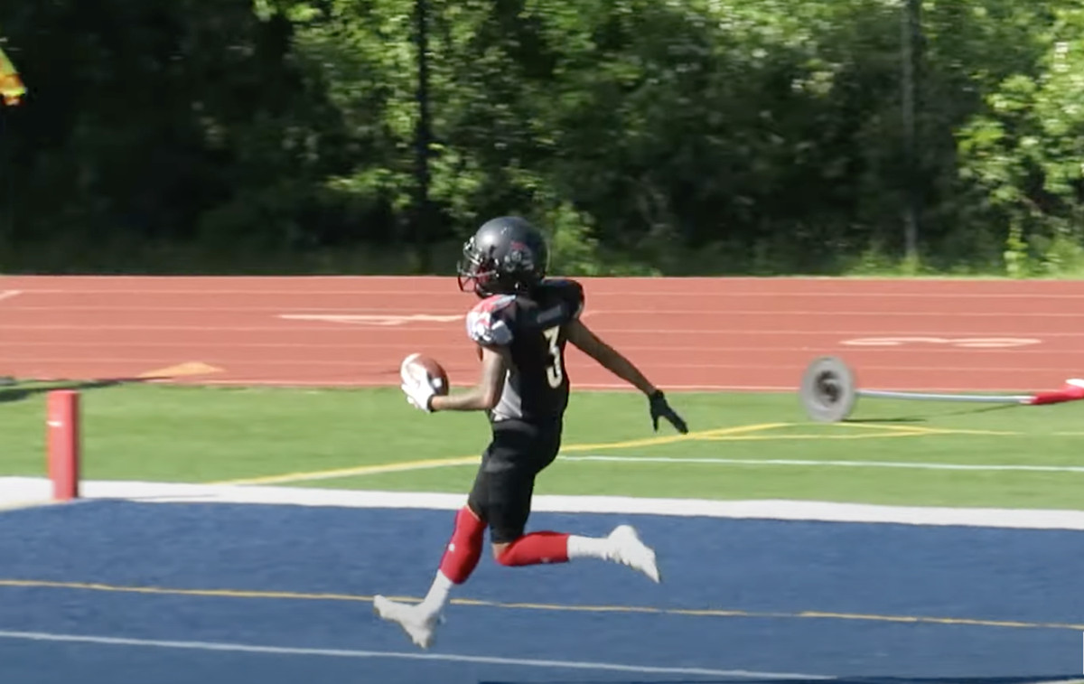 Une joueuse de football féminin court dans la zone des buts.