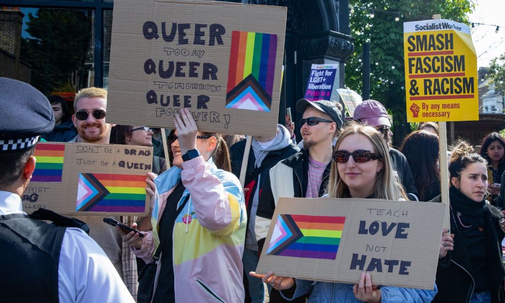 Les gens brandissent des pancartes en faveur de la communauté LGBTQ + et un événement de traînée devant un officier de la police du Met à Londres