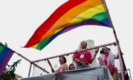 People hold up a rainbow LGBTQ+ Pride flag during a parade in South Korea