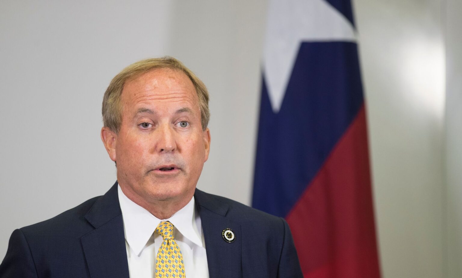 Le procureur général du Texas, Ken Paxton, lance de nouvelles attaques contre les soins de santé trans Texas attorney general Ken Paxton, who has repeatedly pushed back on trans rights in the states, speaks to people off camera while wearing a white shirt, yellow tie and dark suit jacket