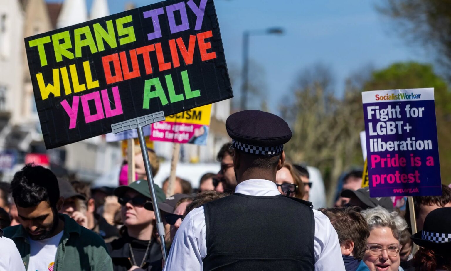 Diffuser la joie et la comédie queer est essentiel, déclare la dramaturge Octavia Nyombi A person holds up a sign reading 'Trans joy will outlive you all' in support of the LGBTQ+ community and a drag event at the Honor Oak Pub as the individual stands in front of a Met Police officer