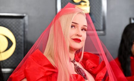 Kim Petras wears a sheer red veil on the red carpet at the 2023 Grammy awards.