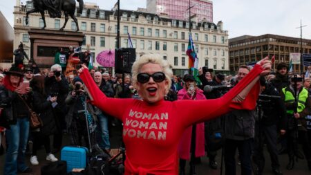 Anti-trans campaigner Posie Parker stands at a rally wearing a top reading "woman, woman, woman"