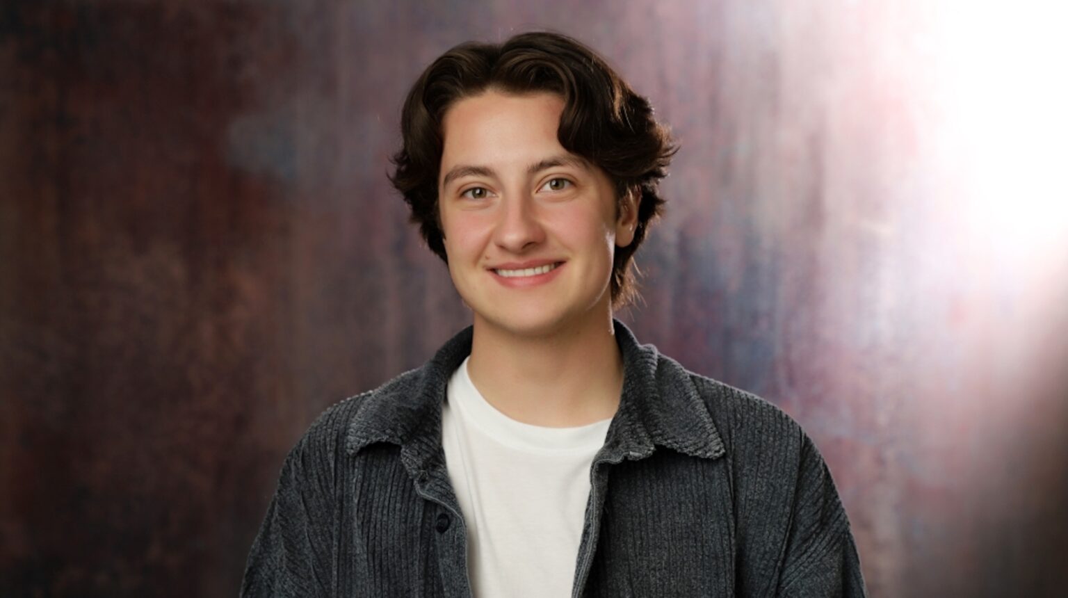 L’activiste Tate Smith prévient que les entreprises ne «prévoient» pas l’inclusion trans Trans activist Tate Smith is posing for the camera. He has on a green shirt with a white shirt underneath.