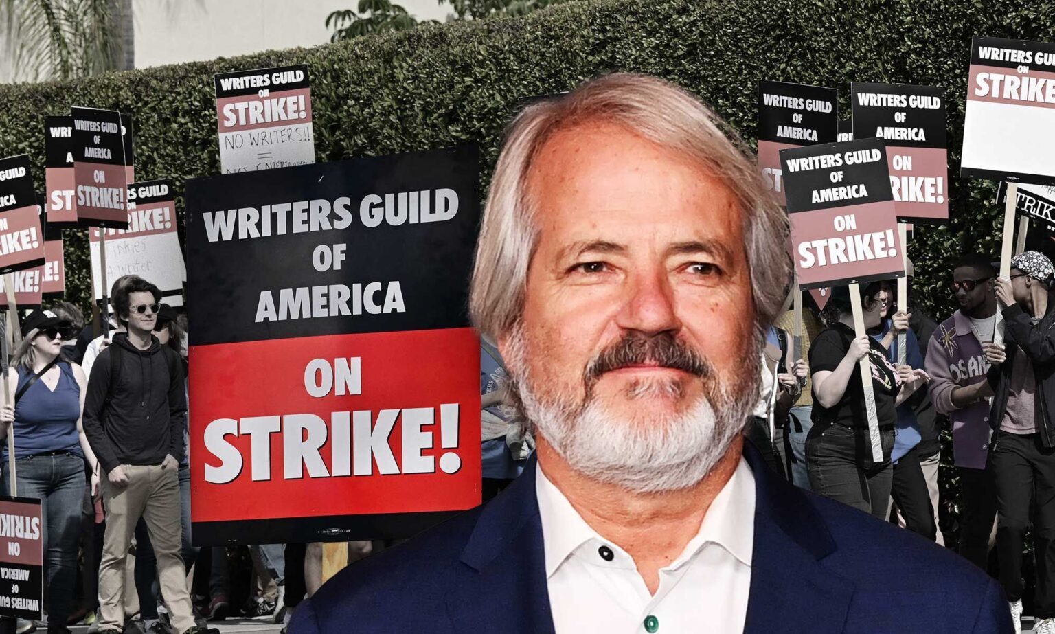 Le créateur du silo, Graham Yost, explique pourquoi les écrivains « en difficulté » devaient se mettre en grève Graham Yost, creator of Silo, pictured against the background of a writers' strike protest with a sign saying "writers guild of America on strike!"