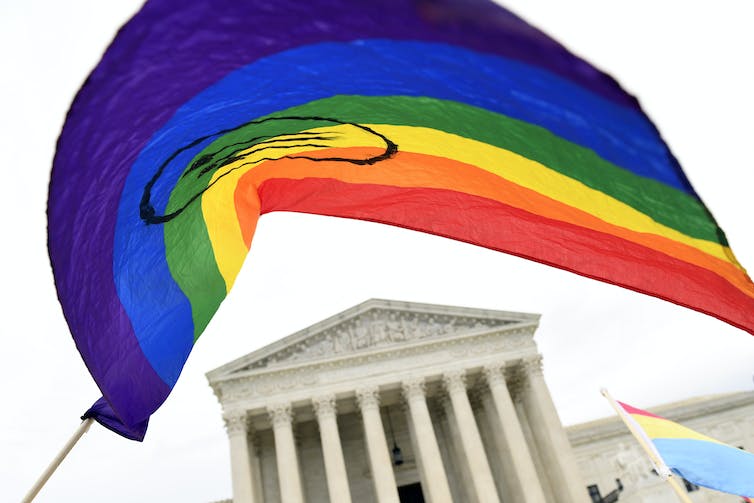le drapeau arc-en-ciel est vu avec le bâtiment à colonnes de la cour suprême en arrière-plan