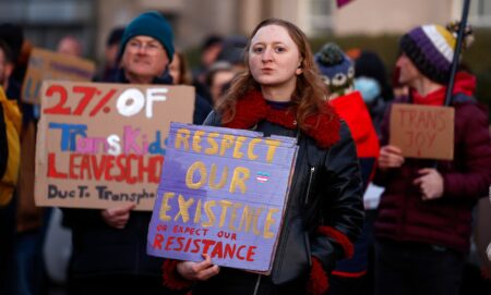 A group of trans activists hold signs of solidarity.