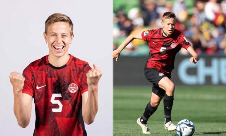 Canadian footballer Quinn wears a red and black uniform as they chase a football along the field at the 2023 Women