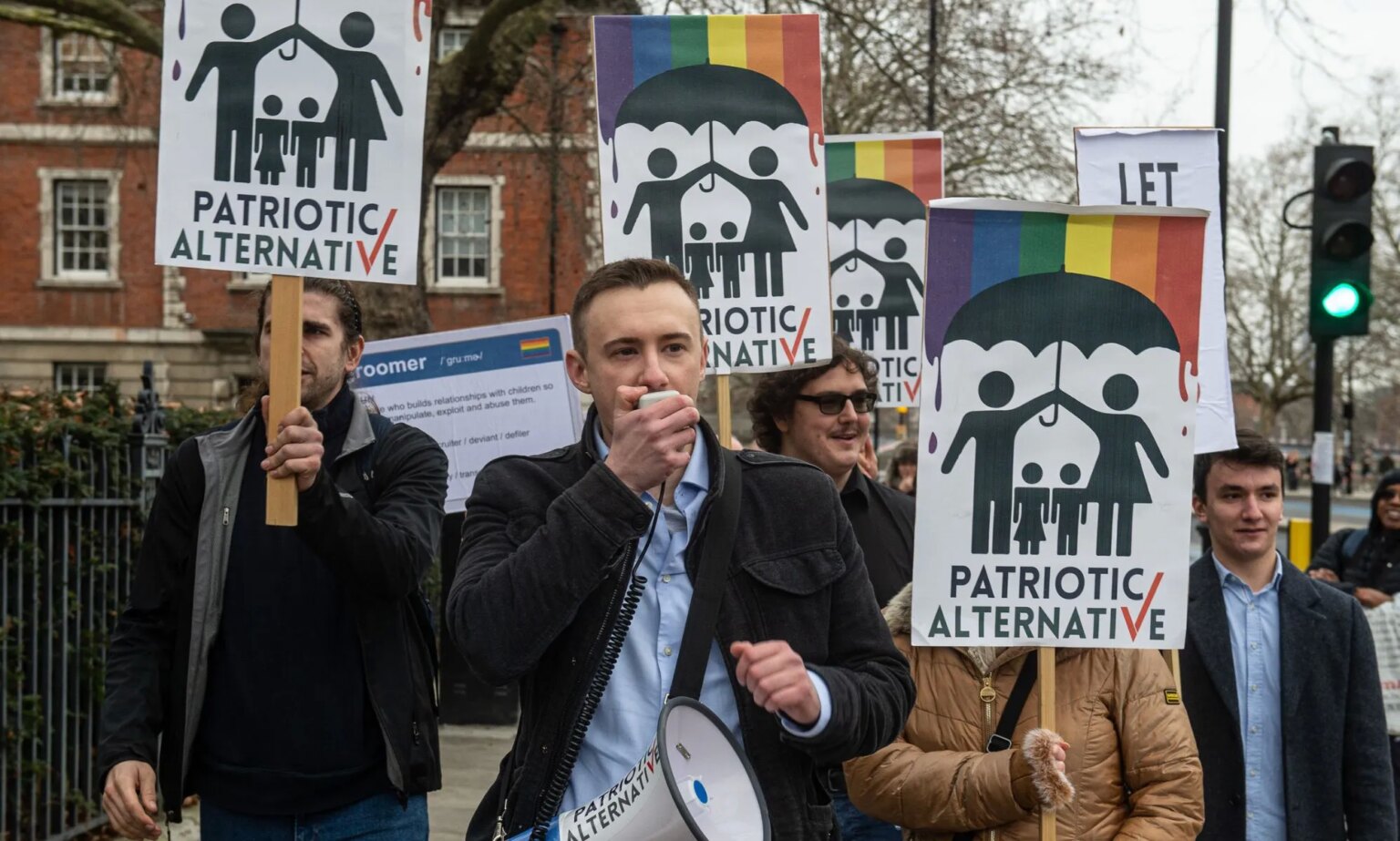 Un manifestant anti-drag de la Tate Britain reconnu coupable d’atteinte à l’ordre public suite à une diatribe pédophile A man holds a megaphone while people behind him hold up anti-LGBTQ+ Patriotic Alternative signs.