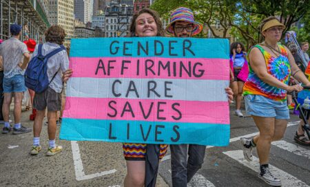 A person holds up a sign during an LGBTQ+ demonstration that reads