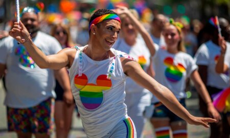 A person dances during a DIsney pride parade.