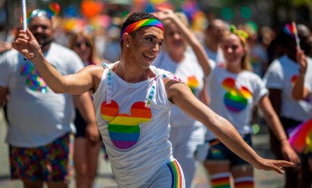 A person dances during a DIsney pride parade.