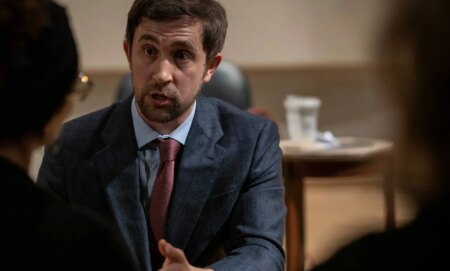 New College of Florida trustee Christopher Rufo speaks to two people during a meeting.