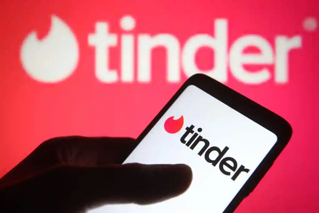 Un téléphone avec le logo Tinder, devant un autre logo Tinder