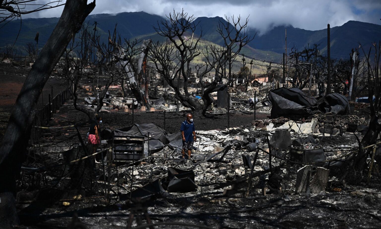 « Tout a disparu en quelques minutes » : comment les homosexuels de Maui se sont réunis après des incendies de forêt dévastateurs A ground view of the devastation left behind in Maui, Hawaii after wildfires burned down Lahaina. In the picture, there are two people shifting through the rubble, blackened trees and the remains of buildings