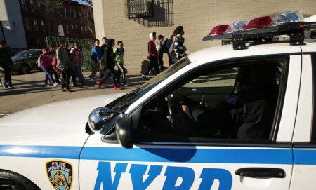 An NYPD police car next to a group of children heading to school.