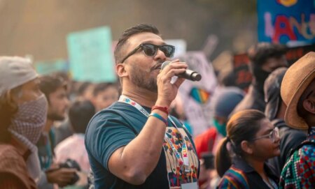 Navonil Das, an LGBTQ+ activist from India, pictured speaking into a microphone at a demonstration.