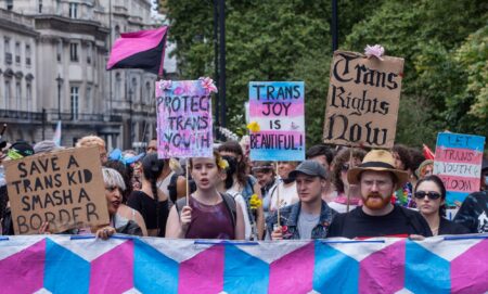 Various people hold up signs calling for trans youth and adults to be protected amid repeated attacks on healthcare rights, closure of gender identity services in England and more in the UK