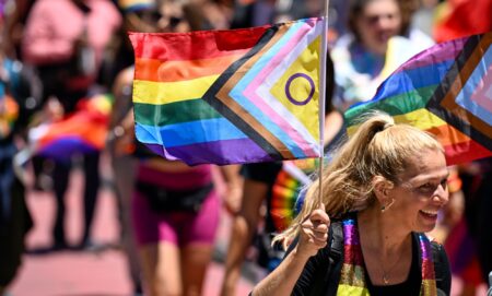 Woman carries an inclusive Pride flag during San Francisco Pride march in June 2022