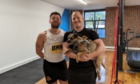 Daniel Browne and Chris Woods of the Leeds People's Gym pictured in their gym posing with a dog.