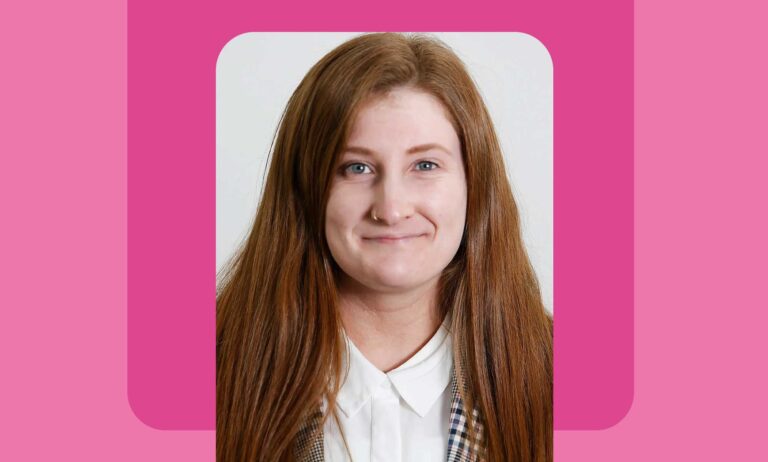 This is an image of a woman. She has long red hair and a fair complexion. She has her nose pierced.