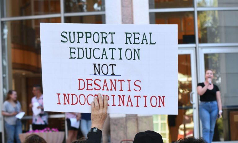 During a Florida protest, a protestor holds up a sign reading
