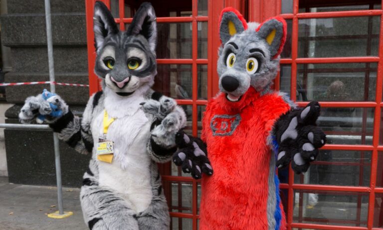 Two people, who are part of the furry community, dress in colourful fursuits as they pose outside in London for a photograph