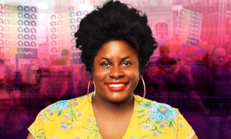 A Black woman is smiling center in the image. She is wearing a bright yellow top. Behind her is a creatively overlay of a Pride Parade in pink and black hues.