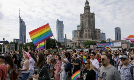 People march through the street with rainbow flags during the Warsaw Equality Parade in Poland in 2023